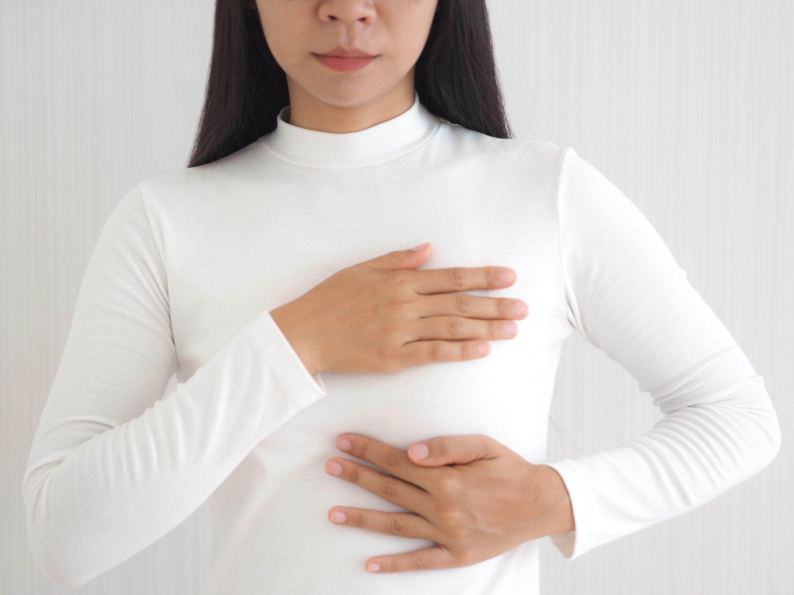 breast cancer and breast pain in asian woman and she use hand touching her breast and symptom of change size or shape of one or both breasts use for medicine product or health care concept.