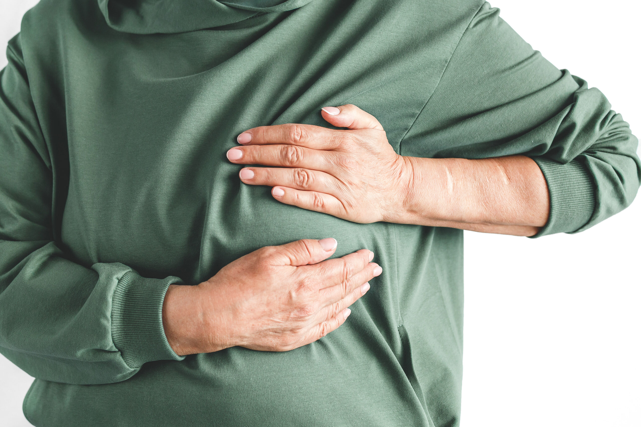 Close up green hoodie holding his chest with both hands suffering from breast pain