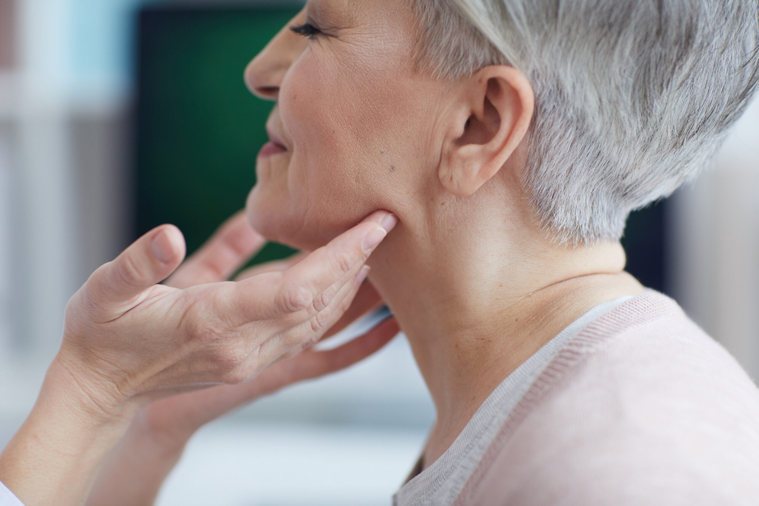 doctor examining smiling senior woman during neck exam