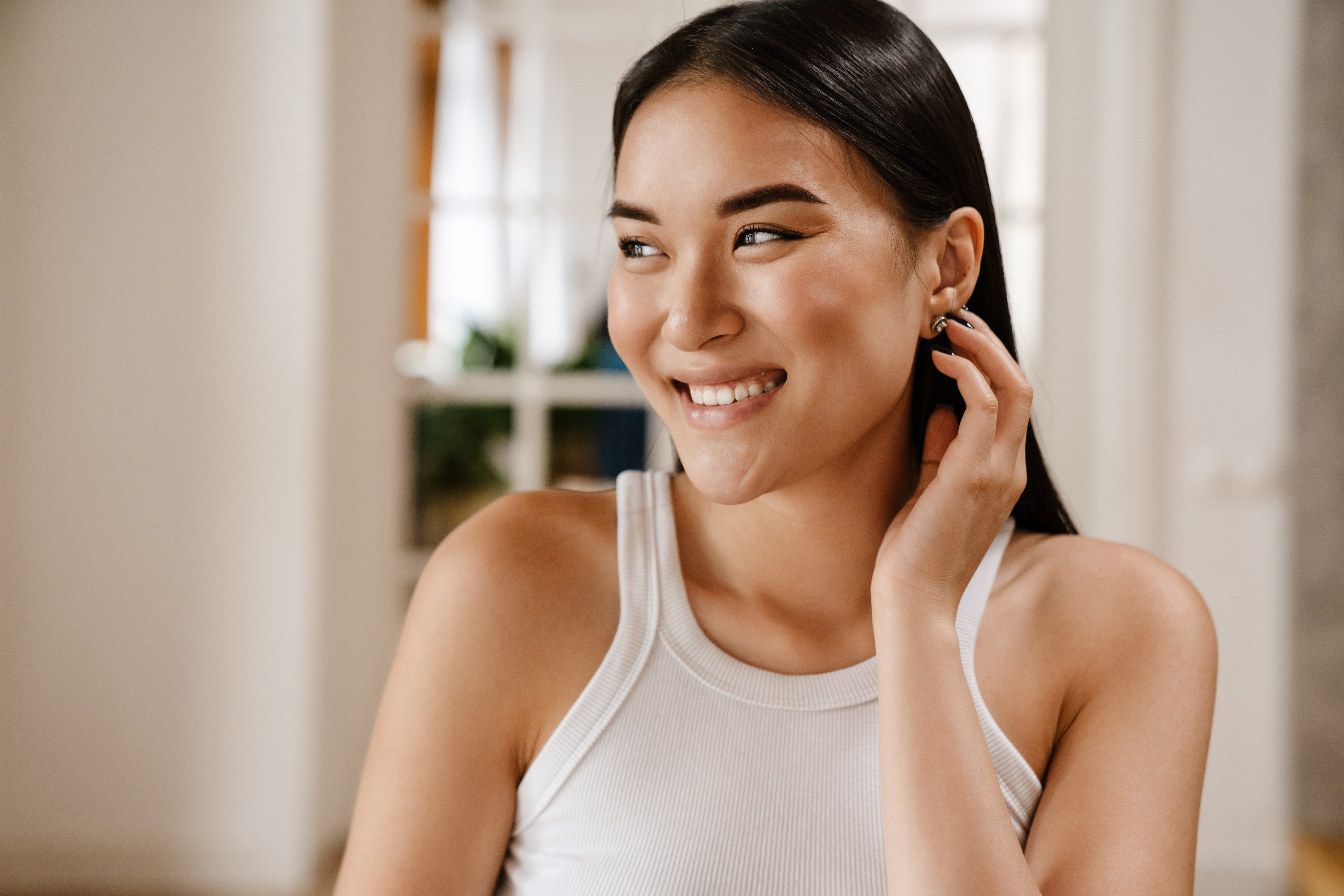 woman in white sleeveless t-shirt adjusting, her hair