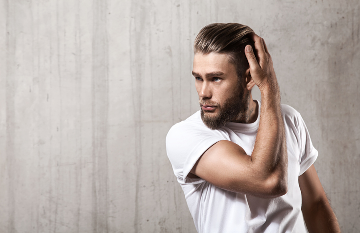 Handsome Bearded Man In A Blank White T Shirt With Stylish Hair On A Cement Wall